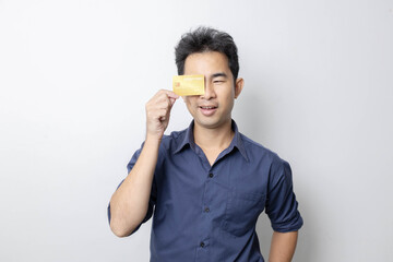 A man stands holding a cell phone, laptop, and credit cards. He is smiling happily and making...