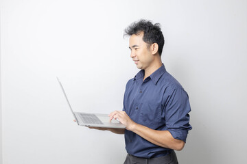 A man stands holding a cell phone, laptop, and credit cards. He is smiling happily and making...