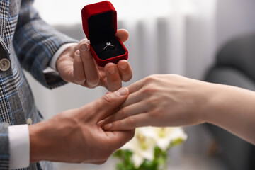 Fototapeta premium Man with engagement ring making marriage proposal to his girlfriend indoors, closeup