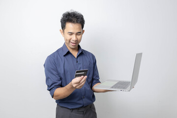 A man stands holding a cell phone, laptop, and credit cards. He is smiling happily and making various gestures for the camera.

