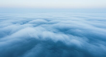 Obraz premium Ethereal Blue Cloudscape: Aerial View of Dense, Dreamy Clouds at Dawn