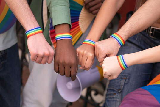 Activists wearing rainbow bracelets, symbolizing lgbtq pride and equality, join fists in solidarity