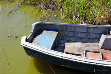 The stern of the boat is visible among the reeds along the shore of Lake Jamno in Mielno, Poland