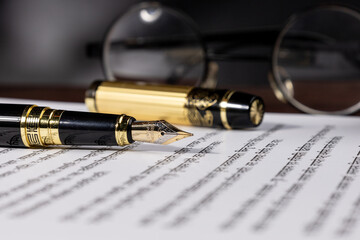 Elegant fountain pen placed on a sheet of paper, symbolizing law, notary, and attorney work. A...