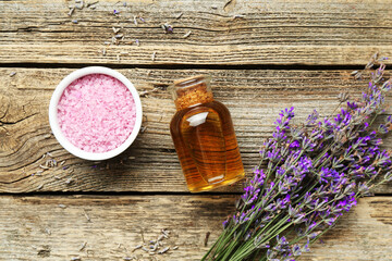 Obraz na płótnie Canvas Lavender essential oil, flowers and sea salt on wooden table, flat lay