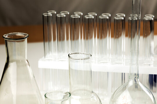 Laboratory equipment including various glass beakers and test tubes arranged on a white surface. 