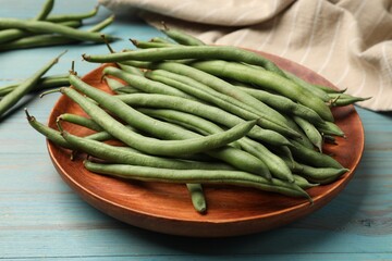 Many raw green beans on blue wooden table, closeup