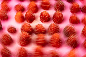 A close-up view of numerous red strawberries arranged on a pink background. 