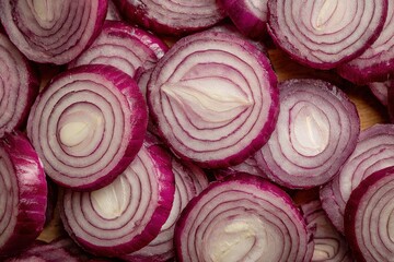 Fototapeta premium Radiant slices of red onion arranged artistically on a wooden kitchen surface