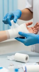 Obraz premium Medical professional applying bandage on patient hand with protective gloves in clinical environment.