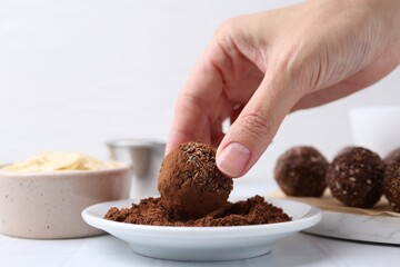 Woman making homemade candies at white table, closeup