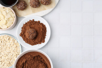 Making homemade candies. Chocolate balls and ingredients on white tiled table, flat lay. Space for...
