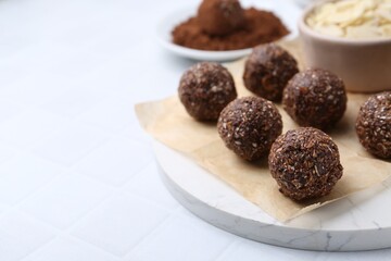 Making homemade candies. Chocolate balls and ingredients on white tiled table, closeup. Space for text