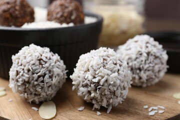 Delicious homemade candies with coconut flakes on table, closeup