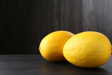 Whole ripe melons on black wooden table. Space for text