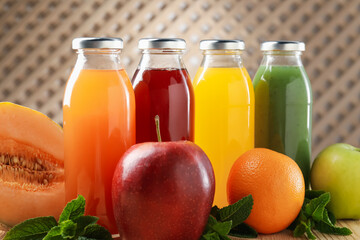 Tasty juices in glass bottles, fresh ingredients and mint on wooden table indoors, closeup