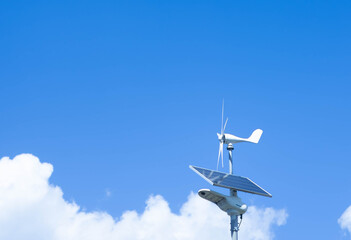 Solar panel and wind turbine system against a clear blue sky