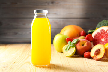 Tasty juice in glass bottle, fresh ingredients and basil on wooden table against brown background, closeup