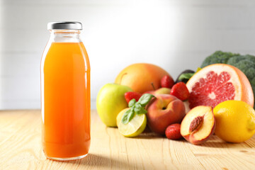 Tasty juice in glass bottle, fresh ingredients and basil on wooden table against light grey background, closeup