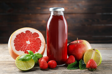 Tasty juice in glass bottle, fresh ingredients and herbs on wooden table against brown background, closeup