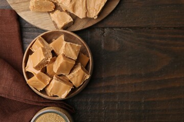 Homemade caramel candies and brown sugar on wooden table, flat lay. Space for text