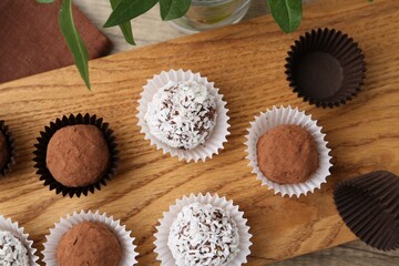 Delicious homemade candies with cocoa powder and coconut flakes on table, top view