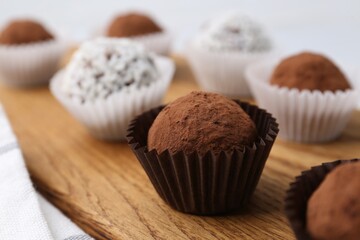 Delicious homemade candies with cocoa powder and coconut flakes on table, closeup
