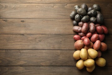 Different types of potatoes on wooden table, flat lay. Space for text
