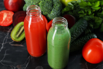 Tasty juices in glass bottles and ingredients on black marble table, closeup
