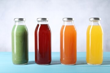 Tasty juices in glass bottles on light blue wooden table