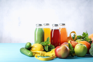 Tasty juices in glass bottles and ingredients on light blue wooden table
