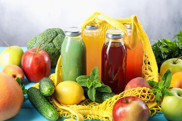 Tasty juices in glass bottles and ingredients on light blue wooden table, closeup