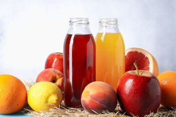 Tasty juices in glass bottles and fresh fruits on table, closeup