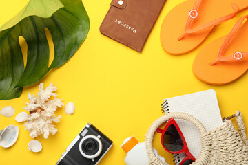 Time for summer vacation. Passport, notebook, camera, beach accessories and green leaf on yellow...