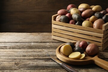 Different types of potatoes and knife on wooden table, closeup. Space for text