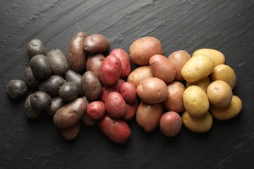 Different types of potatoes on black table, flat lay