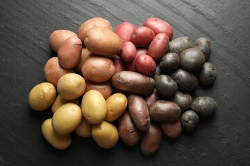 Different types of potatoes on black table, flat lay