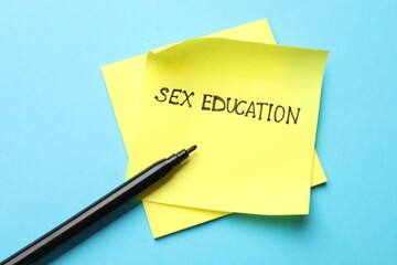 Sticky notes with phrase Sex Education and felt tip pen on light blue background, top view