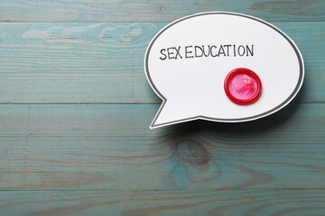 Speech bubble with phrase Sex Education and condom on blue wooden background, top view