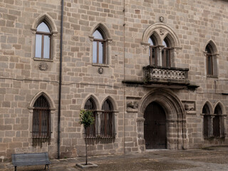 Palace of the dukes of san carlos showing stone walls, arched windows, and balcony in trujillo, spain