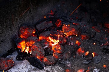 Glowing embers of charcoal in a dark setting, showcasing the vibrant orange and red hues, creating...