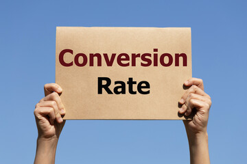 Conversion rate text on paper holding by a woman's hand with blue sky background