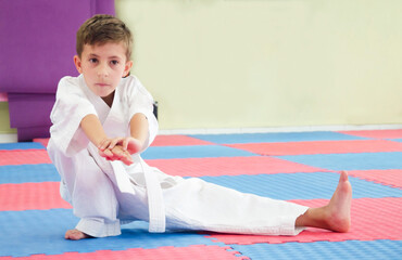 Karate boy doing stretching at workout.Child in kimono. Martial arts. 極真会(Karate Kyokushin)	
