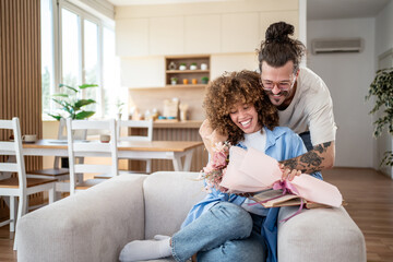 Man giving flowers to woman at home: romantic surprise