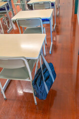 スクールバックの掛った教室にある机と椅子の後方からのクローズアップ、学校イメージ