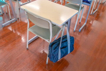 スクールバックの掛った教室にある机と椅子の後方からのクローズアップ、学校イメージ