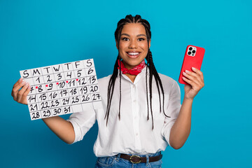 Young woman holding a calendar and smartphone in casual attire with stylish accessories on a...