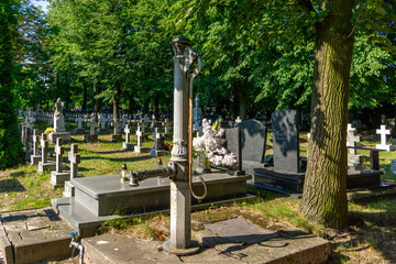 Military cemetery in Kalisz with rows of white crosses, historic tombstones, and an old water pump...