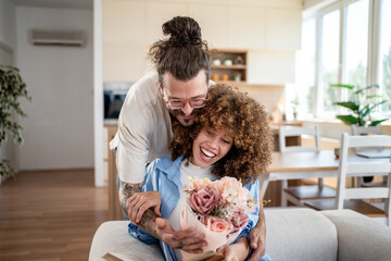 Happy couple sharing a tender moment with flowers at home