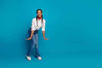 Charming young woman in casual white shirt posing with a bright smile against a blue background